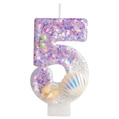 the number five candle is decorated with pink and purple glitters, pearls and seashells