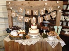 a table topped with cakes and desserts next to a wooden sign