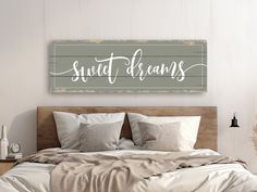 a wooden sign that says sweet dreams above a bed