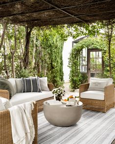 an outdoor living area with wicker furniture and pillows on the floor, surrounded by greenery