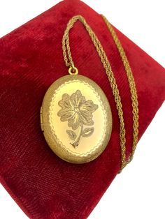 Description: A large vintage 12K gold filled necklace by Marathon Co.  This etched oval locket necklace features a floral design on the front and a plain/shiny back. The front has a central etched flower with stem and two leaves.  The flower is surrounded by a double zigzag edging around it.  The outer oval has a stipple or textured finish to it (as does the flower and leaves inside).   The locket is larger than most, and has a chain that is 24" long, or Matinee length. Very unique retro era locket.  The locket opens as intended and closes securely.   The locket would hold two oval shaped photos - one on each side. Currently, the 2 photo wells have the original photo frames and blue paper backing intact. The vintage locket hangs from a vintage 24" 12K gold filled twisted link rope chain (a Vintage Gold Locket Necklace With Oval Link, Vintage Gold Oval Link Locket Necklace, Gold Oval Pendant For Vintage Collection, Vintage Oval Engraved Locket Necklace, Vintage Gold-tone Engraved Necklace, Vintage Oval Link Jewelry Gift, Vintage Gold Locket Necklace Stamped 14k, Vintage Gold Locket Jewelry, Collectible Oval Yellow Gold Necklaces