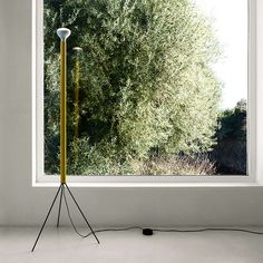 a floor lamp sitting in front of a window next to a light pole with two lights on it