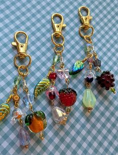 four different types of charms on a blue and white checkered tablecloth with gold chains