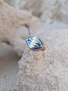 a blue and white ring sitting on top of a rock