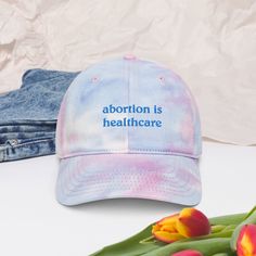 "This tie-dye hat features professionally embroidered \"abortion is healthcare\" across the center. Make a statement with your fashion, while sporting a 100% cotton product. Well suited for both indoor and outdoor events as it is breathable, and provides sun protection. Additional thread colors and tie-dye patterns also available in the shop - DM for custom requests. * 100% cotton * Unstructured, 6-panel, low profile * Pre-curved visor * Tri-glide buckle closure * One size fits most * LGBTQ+ wom 90s Hats, Tie Dye Hat, Christian Hats, Mom Hats, Pastel Tie Dye, Hat Embroidery, Embroidered Hat, Tie And Dye, Embroidered Hats