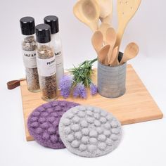 spices and spoons are on a cutting board next to a pot holder with wooden spoons