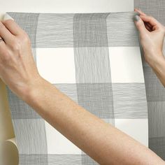 a woman is painting the back of a checkered wallpaper with grey and white stripes