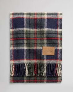 a blue and green plaid blanket on a white background with a brown leather tag hanging from it