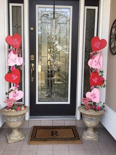 two flower pots with hearts on them sitting in front of a door decorated for valentine's day