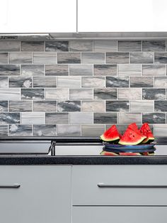 watermelon slices sit on the stove top in this modern kitchen setting with gray cabinets and tile backsplash