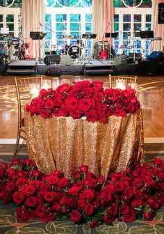 a table with red roses on it in front of a stage set up for a concert