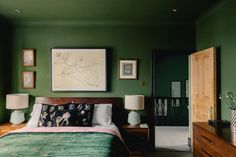 a bedroom with green walls and pictures on the wall above the bed, along with two nightstands