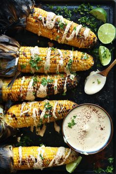 grilled corn on the cob with ranch dressing and lime wedges next to it