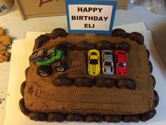 a birthday cake with cars on it and a sign that says happy birthday ell