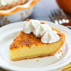 a slice of pie with whipped cream on top sits on a plate next to a fork