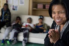 a woman sitting on top of a white couch next to other people in a living room