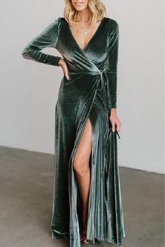 a woman wearing a green velvet wrap dress with thigh high slits and long sleeves