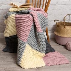 a crocheted blanket sitting on top of a wooden chair next to a basket