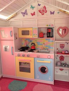 a child's play kitchen with pink, yellow and blue accents on the walls