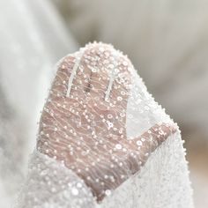 a close up of a person's hand wearing a wedding dress with beading on it