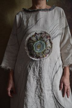 a woman is wearing a white dress with a flower on it's chest and has her hands in her pockets