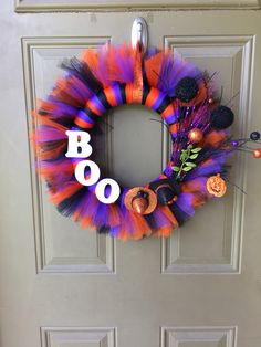 a halloween wreath with boo written on it and decorations hanging from the front door frame