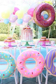 a table topped with donuts covered in frosting and sprinkles next to balloons