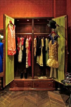 an open wardrobe with clothes hanging on it