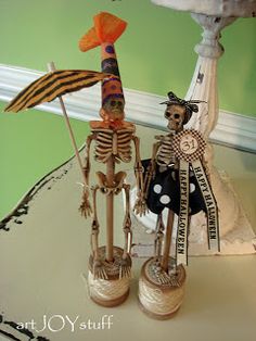 two skeleton figurines are standing next to each other on a table with an umbrella