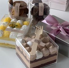 four different types of desserts in plastic containers on a white table with pink ribbon