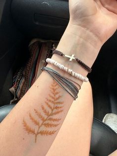 a woman's arm with a cross on it and three bracelets around her wrist