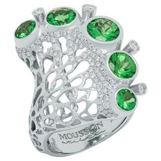 a ring with green and white stones in the shape of an animal's paw