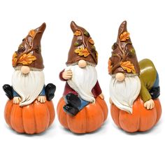 three small gnomes sitting on top of pumpkins