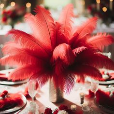 the centerpieces are adorned with red feathers and silver vases for an elegant touch