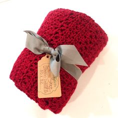 a red crocheted hat with a bow on it and a tag hanging from the side