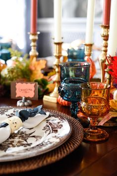 a table set with candles, plates and napkins