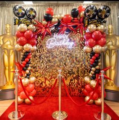 a red carpeted area with an arch decorated with balloons and streamers