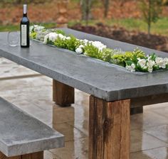 a concrete bench with flowers on it and a bottle of wine