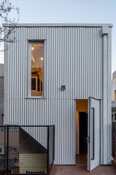 a white building with an open door on the outside and stairs leading up to it