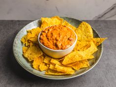 a plate with chips and salsa dip on it, ready to be eaten by someone