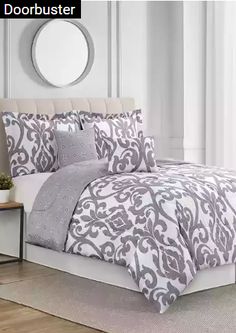 a bed with white and grey comforters in a room