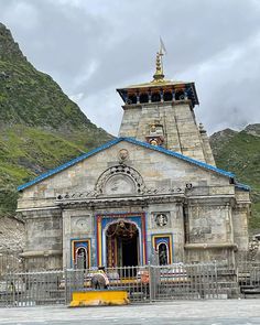 an old building with a blue roof in front of some mountains