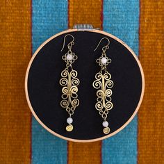 These hammered brass earrings were created by an indigenous artist in Morelos, Mexico. They feature hammered brass spirals and flat drop designs with white quartz beads on each earring. The hook is brass as well. The pieces from this workshop are meant to stand the test of time. All pieces can be returned to their original luster by being cleaned with a slice of lime. This piece was ethically sourced directly from the artist, and the artist explicitly granted permission to resell. White Brass Wire Wrapped Earrings, Slice Of Lime, Ornate Design, Hammered Brass, Le Crochet, Quartz Beads, Beads Handmade, White Quartz, Drops Design