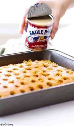 a can of ice cream being poured onto a cake pan filled with graham crackers