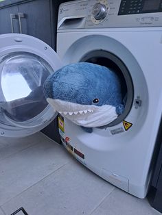 a stuffed shark sitting inside of a washing machine