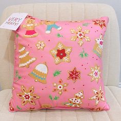 a pink pillow with gingerbreads and christmas cookies on it sitting on a chair