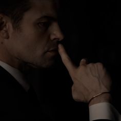 a man in a suit is holding his finger to his nose