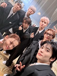 a group of young men in suits posing for a photo with one pointing at the camera