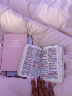 a person is laying in bed with an open book on their lap and the pages are pink