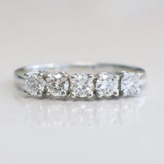 a five stone diamond ring on a white surface